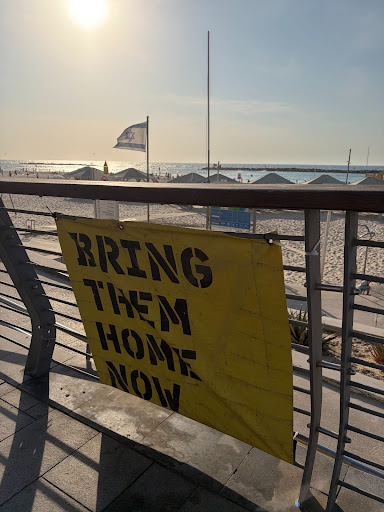 View of Israeli beach featuring sign that says "Bring Them Home Now"